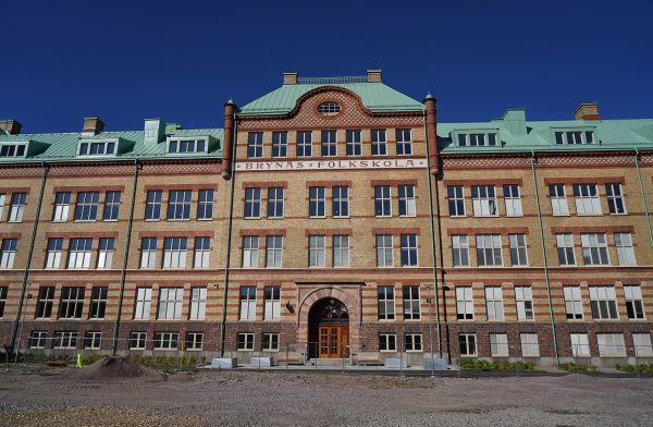 Skolbyggnad, fem våningar i tegel med turkost tak.